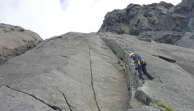 Bilden visar en man med klätterutrustning på en bergvägg