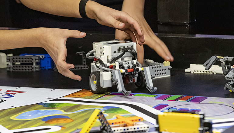 Händer som lyfter en lego-robot