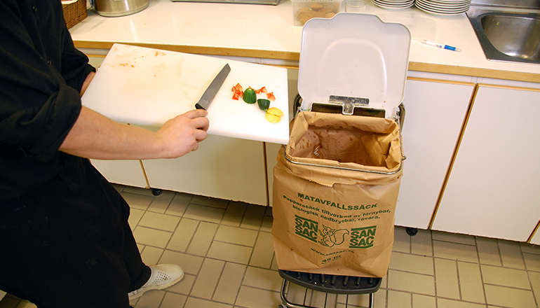 Personal slänger matrester i papperssäck