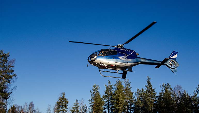 Blå helikopter i luften på låg höjd