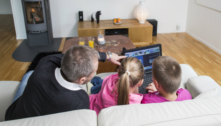 Pappa med två barn tittar på datorn