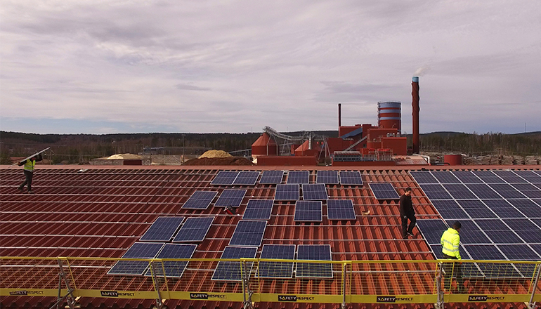 tre män som sätter upp solceller på ett tak